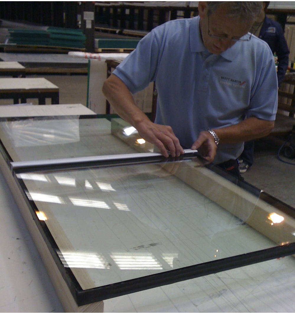 PVC connector cap being pressed into place into the channels of the aluminium glazing connector